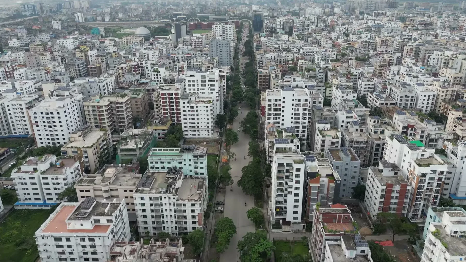 Aerial view along a tree-lined Bashundhara block road with apartment buildings on both sides