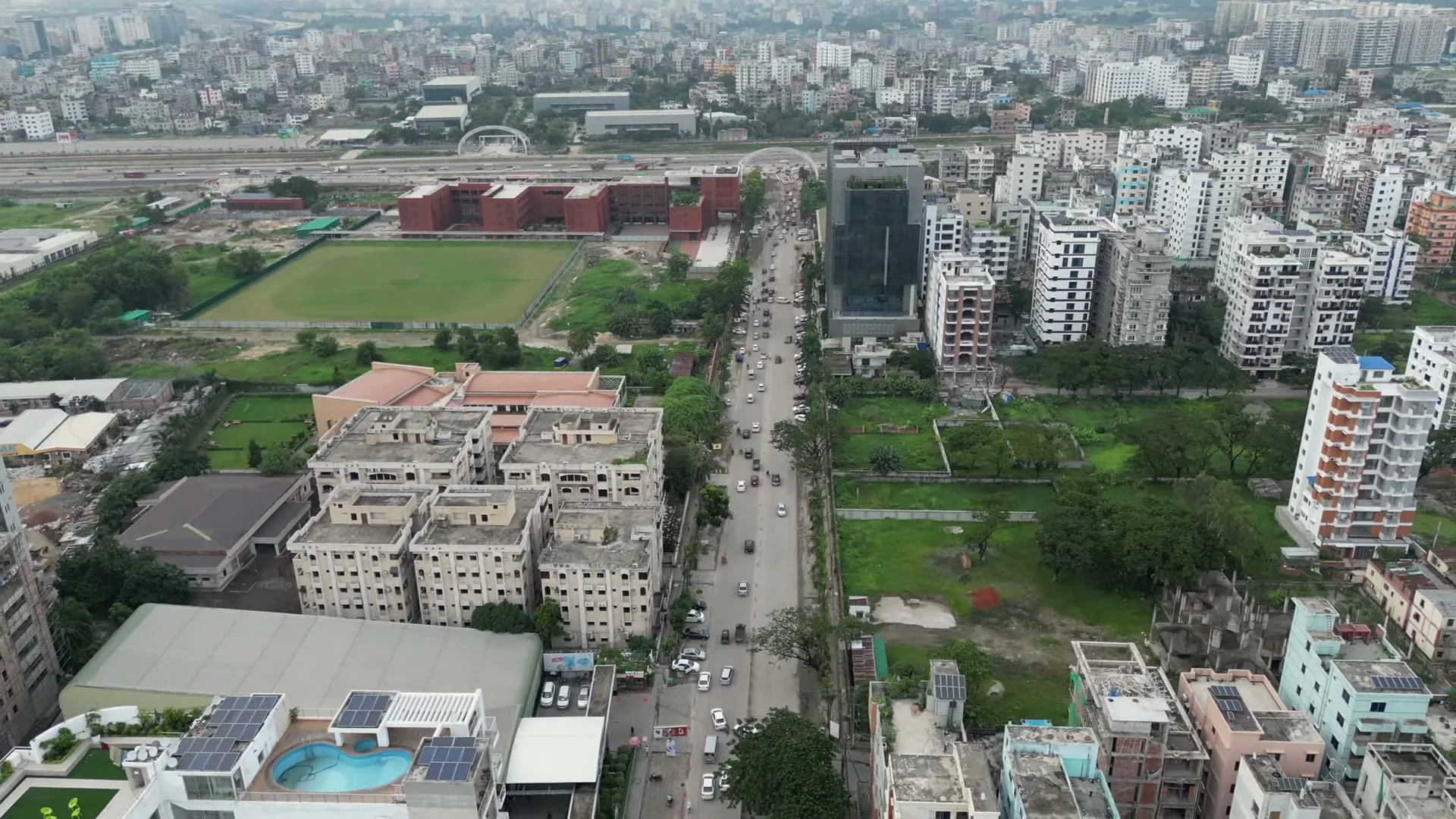 Aerial view of walled, filled residential plots between finished apartment buildings in Bashundhara R/A