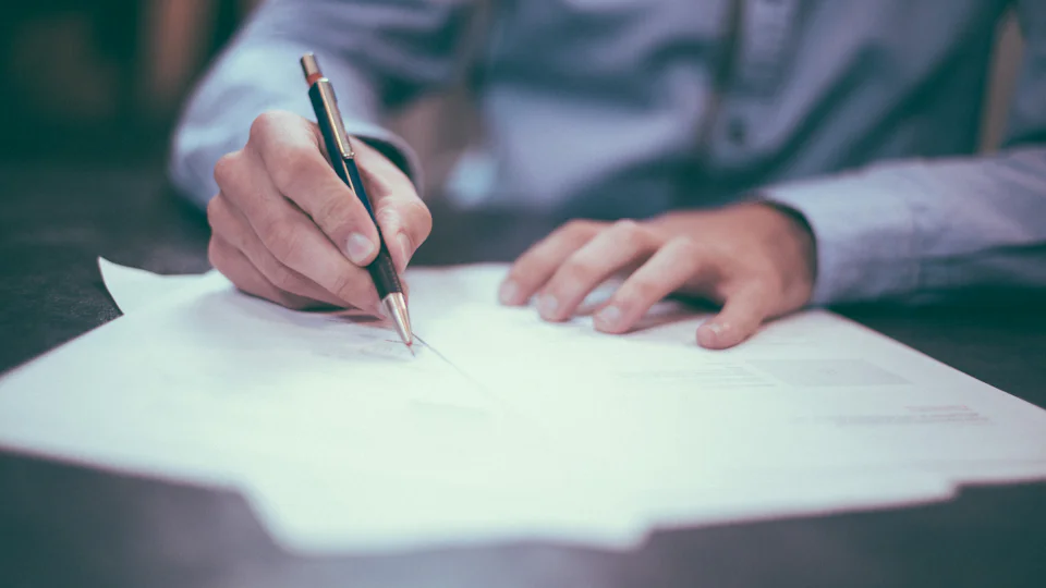 Somebody signing a document at a desk