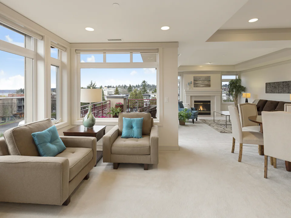 A finished apartment living room, sofas by a window with the city beyond