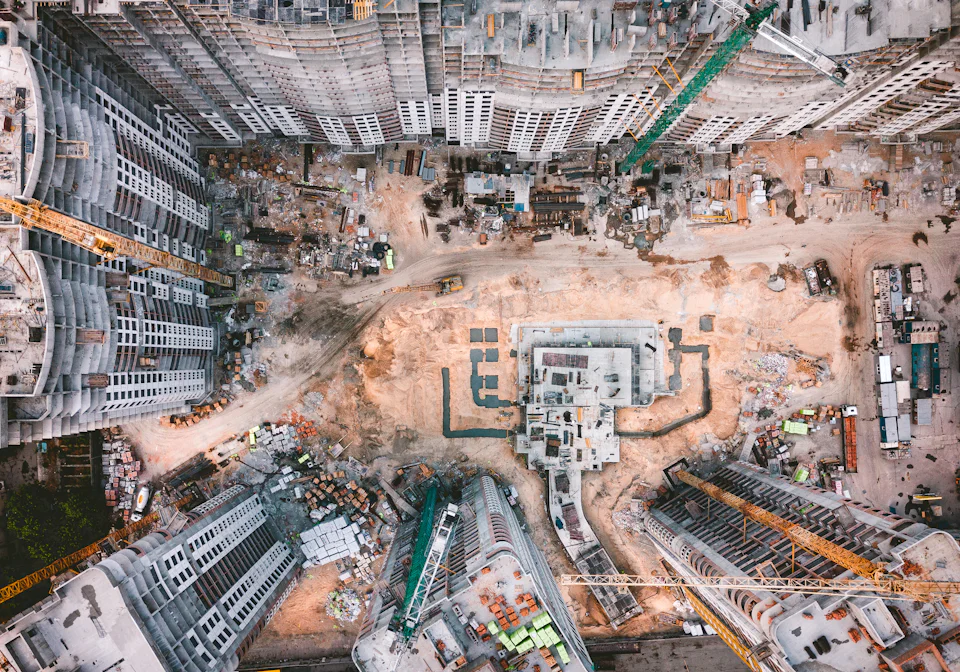 A construction site from above, foundations laid out and cranes at work