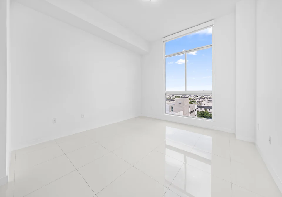 A finished apartment at handover, tiled and empty, looking out over the city